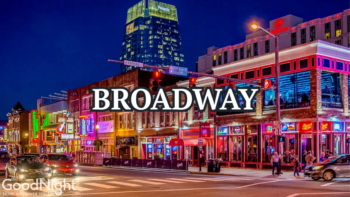 The image captures a bustling Nashville street scene at night, featuring lively neon signage, busy sidewalks packed with people, and high-rise buildings. The energy and excitement of nightlife, dining spots, and live music venues are all on display, embodying the pulse of the city's entertainment district.