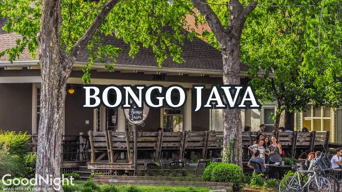 The lively exterior of Bongo Java, featuring an inviting outdoor seating area shaded by greenery where people socialize and enjoy coffee together.